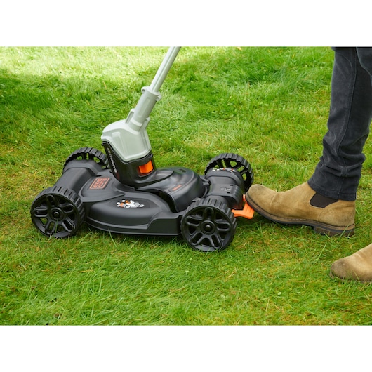 BLACKDECKER CM100 lawn mower attachment on grass, side view, black and orange design with foot pedal.