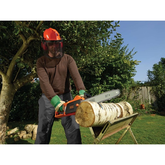 BLACKDECKER CS1835 chainsaw used outdoors to cut log on stand, person wearing safety gear.
