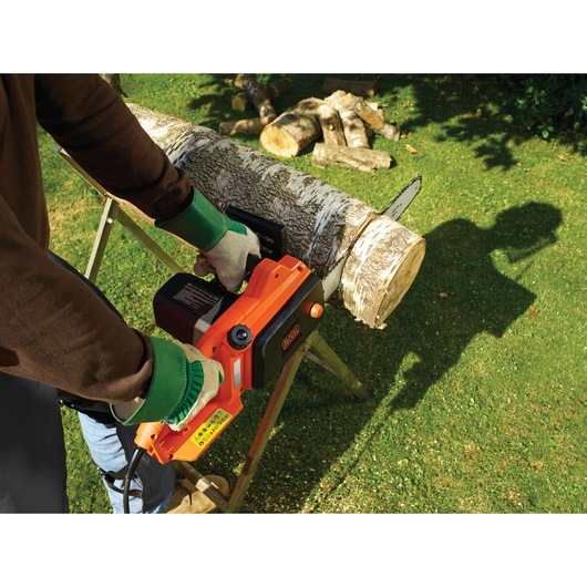 BLACKDECKER CS1835 electric chainsaw cutting log outdoors, orange and black color, close-up view.