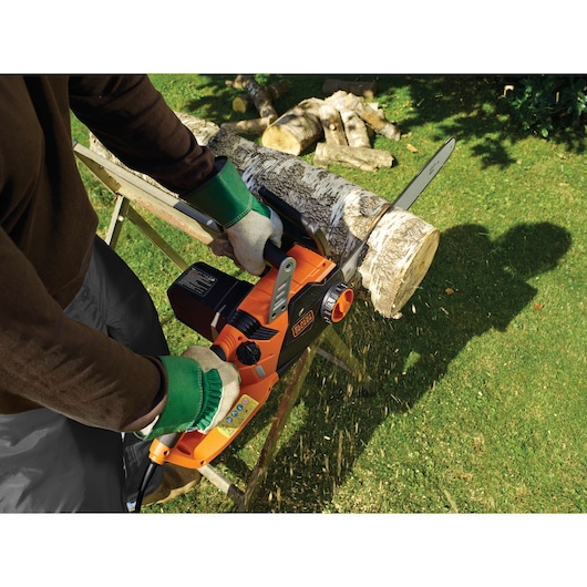 Photo of BLACKDECKER chainsaw CS2245 cutting a log outdoors, orange and black body, person wearing gloves.