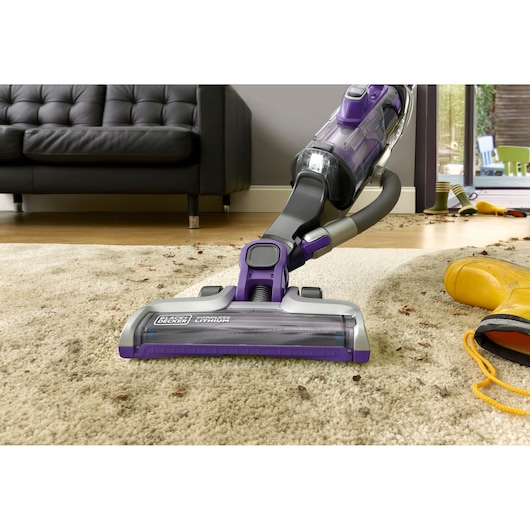 BLACKDECKER cordless vacuum CUA525BHP cleaning dirt on beige carpet in living room, close-up angle.