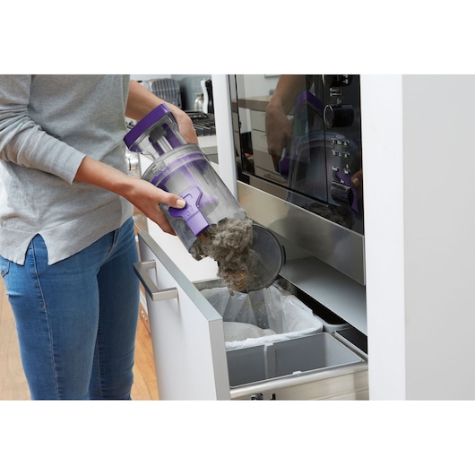 BLACKDECKER CUA525BHP vacuum canister emptied into kitchen trash bin, purple and clear container.