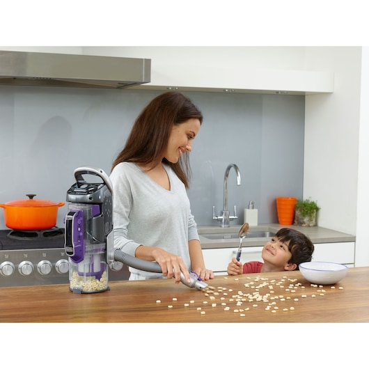 BLACKDECKER CUA525BHP vacuum cleaner used on kitchen counter to clean spilled cereal, child with spoon nearby.