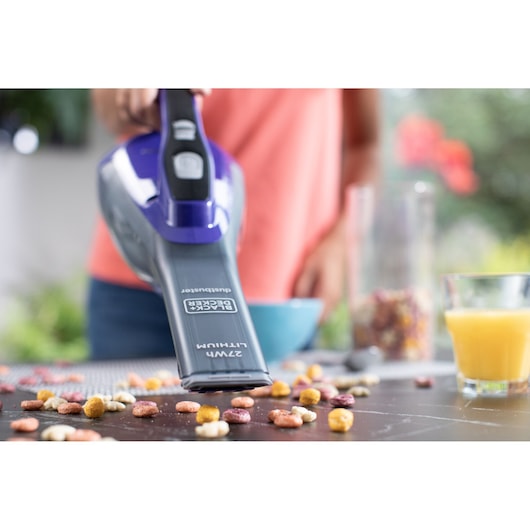 BLACKDECKER DVA325JP07 handheld vacuum cleaning cereal from a table, close-up photography.
