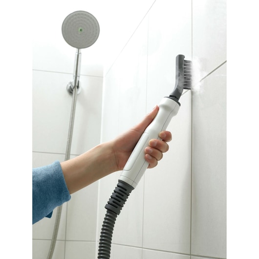 BLACKDECKER FSMH1321 steam cleaner cleaning shower tile grout with brush attachment, close-up.