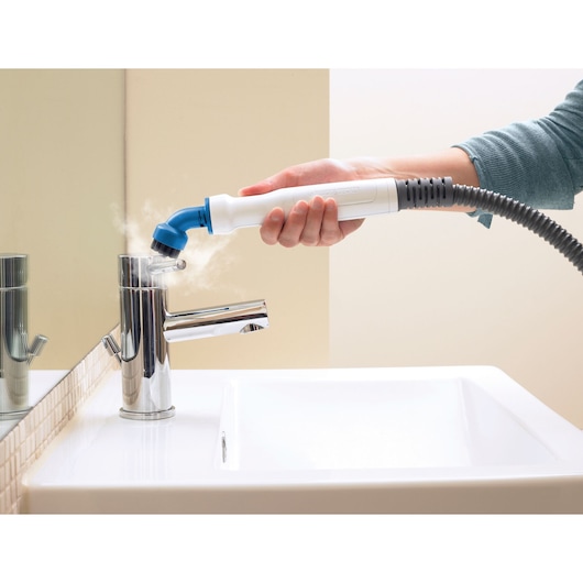 BLACKDECKER FSMH1321 steam cleaner nozzle cleaning chrome faucet in bathroom, side angle.