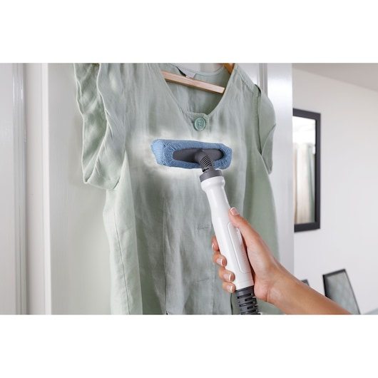 BLACKDECKER FSMH1321 steam cleaner used to refresh a light green shirt on a hanger.