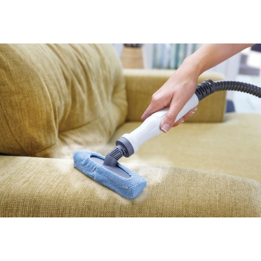 BLACKDECKER FSMH1321 steam cleaner with blue microfiber pad cleaning a yellow fabric sofa.