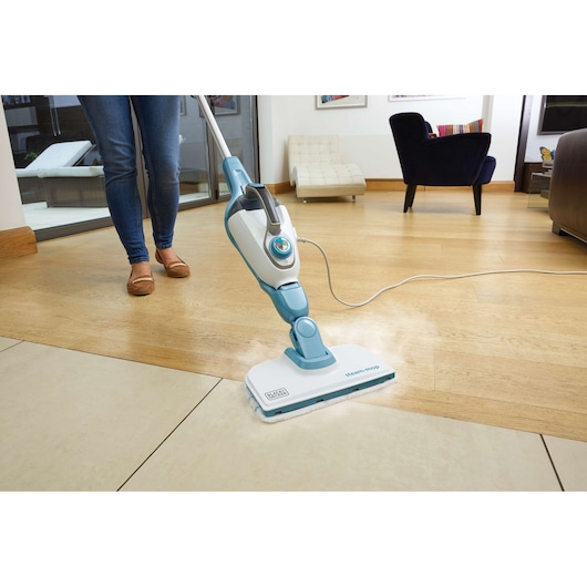 BLACKDECKER FSMH1321 steam mop cleaning light wood and tile floor in modern living room, front angle.
