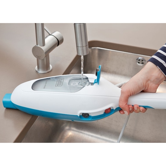BLACKDECKER FSMH13E5 steam mop tank being filled with water in kitchen sink, close-up view.