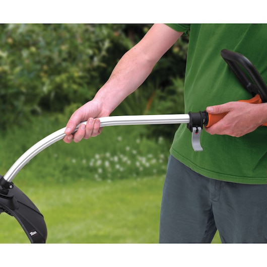 Close-up of a person adjusting the handle on a BLACKDECKER GL7033 grass trimmer outdoors.