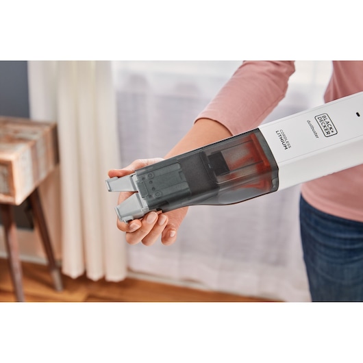 Photo of BLACKDECKER HLVC315J11 cordless handheld vacuum with transparent dust bin, held by a person indoors.
