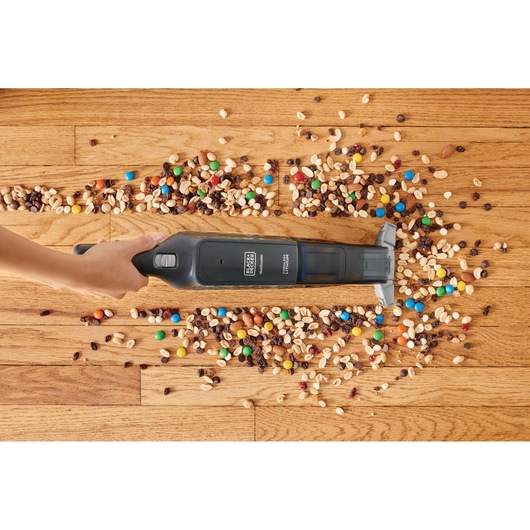 BLACK+DECKER HLVC320B11 handheld vacuum cleaning colorful snacks on hardwood floor, top view
