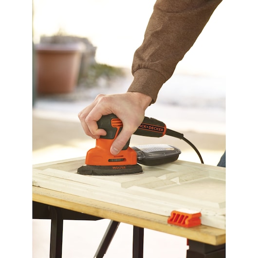 BLACKDECKER KA2500K mouse sander used on wood panel, close-up view.