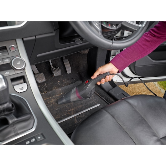 BLACKDECKER NVB12AVA handheld vacuum cleaner used to clean car floor interior.