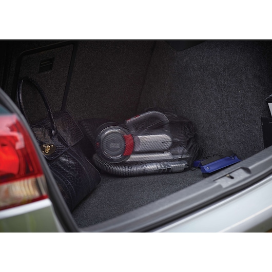 BLACKDECKER PV1200AV handheld vacuum in car trunk with accessories and black bag, side angle.