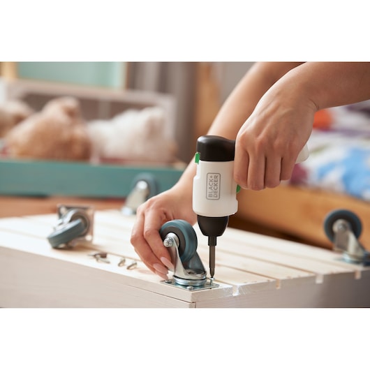 Photo of BLACKDECKER REVSD4C cordless screwdriver assembling caster wheels on a wooden crate.