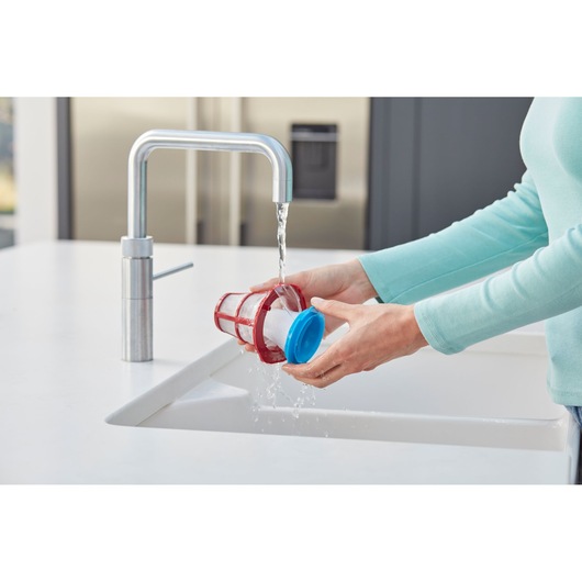 Photo of hands rinsing BLACKDECKER SVB620JW vacuum filter under kitchen faucet in a sink.