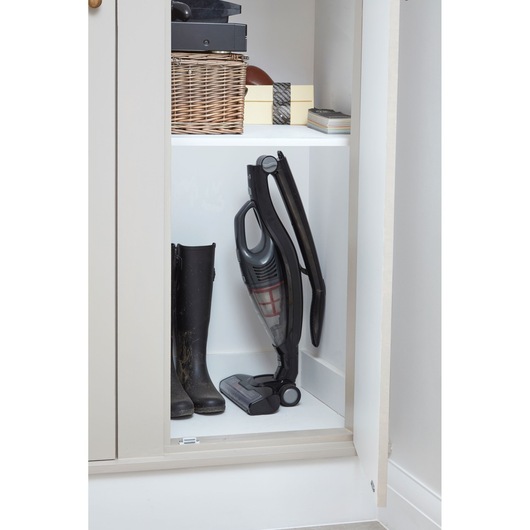 BLACKDECKER SVB620JW cordless stick vacuum cleaner stored upright in a closet next to black boots.