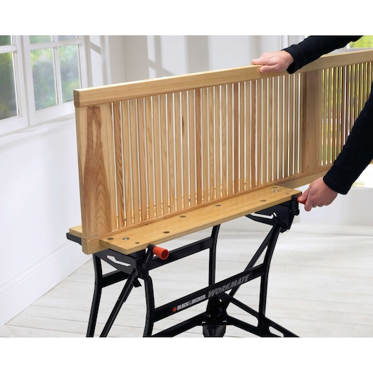 Photo of BLACK+DECKER WM626 workbench clamping a wooden panel in a bright room.